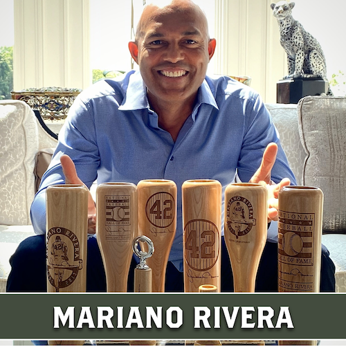 Mariano Rivera smiling behind a collection of wooden Dugout Mugs baseball bat mugs engraved with portraits and designs.